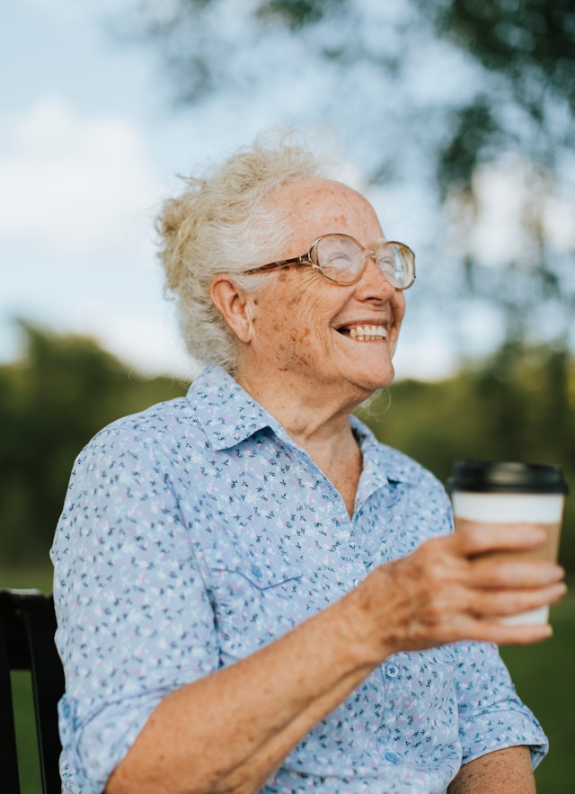 elderly woman smiling while holding cup