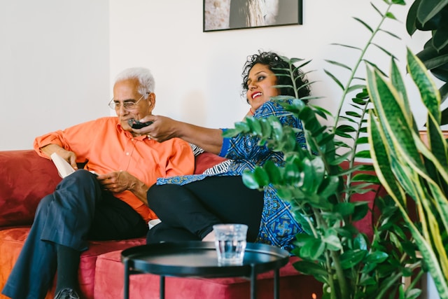 senior couple sitting on sofa together watching TV