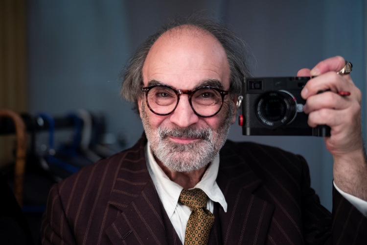David Suchet smiling holding a camera